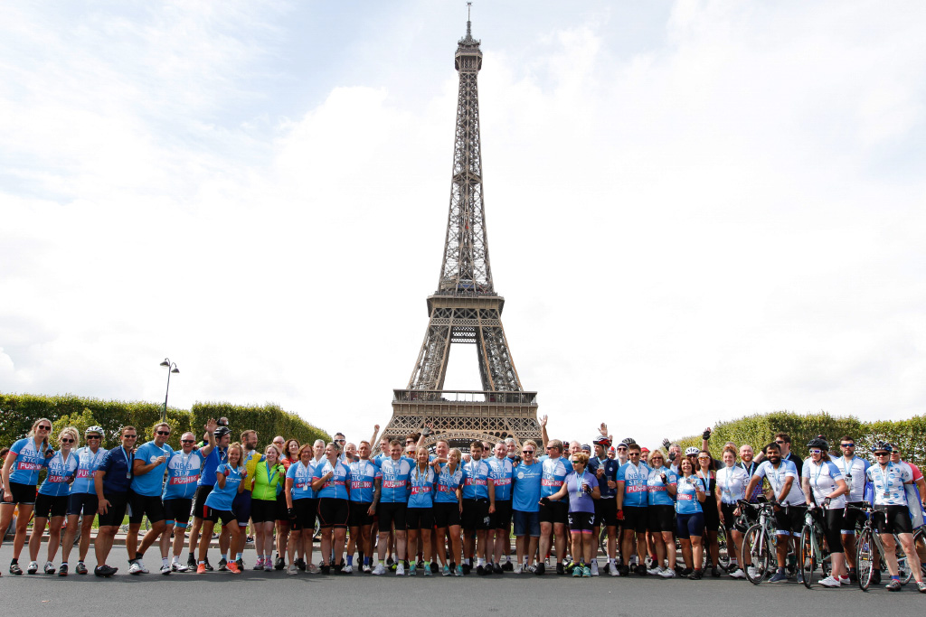 whole group of cyclists lined up in front of the eiffel tower
