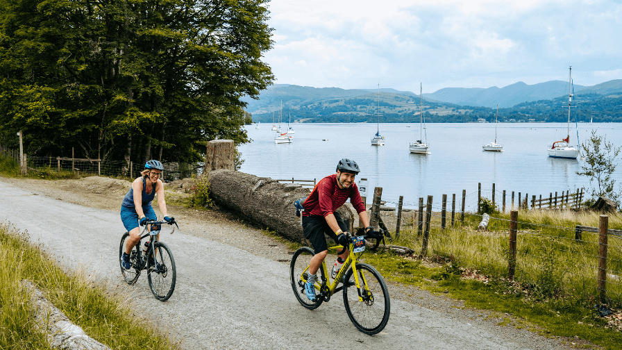 Two cyclists on a road near a lake