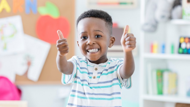 Boy aged four or five giving a thumbs up sign.