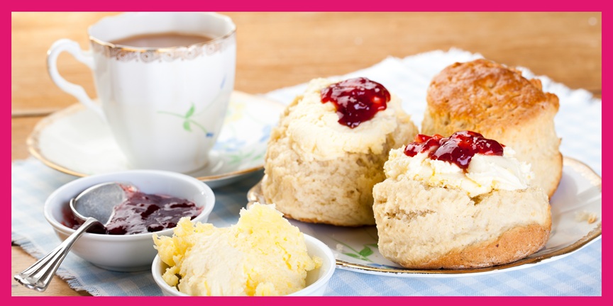 Cup of tea with jam, cream, and scones.
