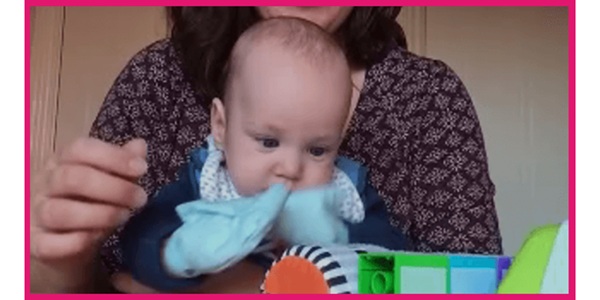 A baby wearing Velcro-covered mittens and exploring Velcro-covered soft bricks.