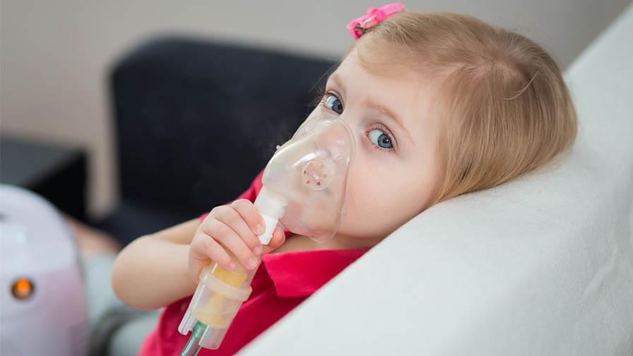 young girl holding oxygen mask over mouth and nose