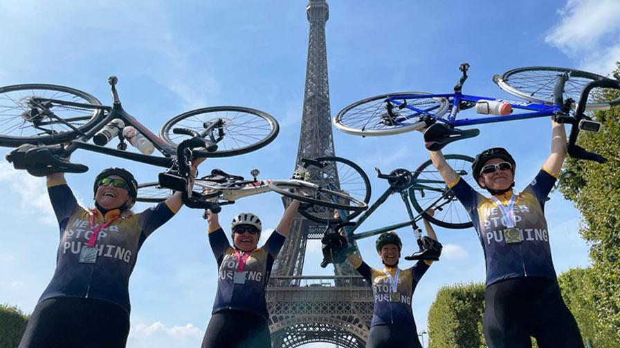 group of cyclists hold bikes above their heads