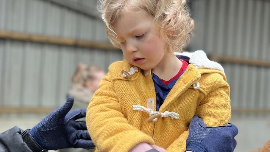 Emmy playnig outside in a yellow coat
