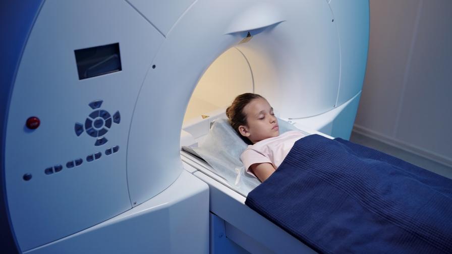 Young girl laying down, about to enter an MRI scanner.