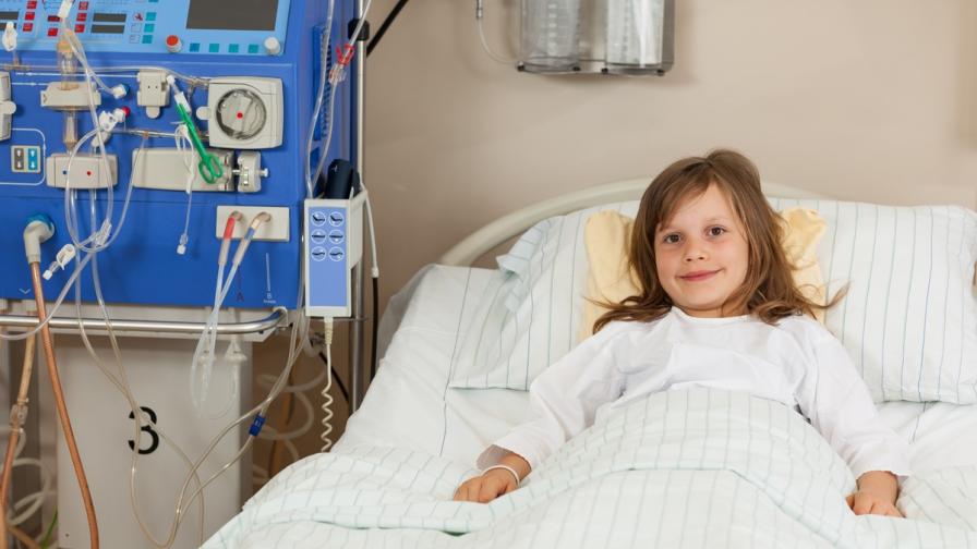 Girl, aged about eight, laying in a hospital bed next to a kidney dialysis machine.