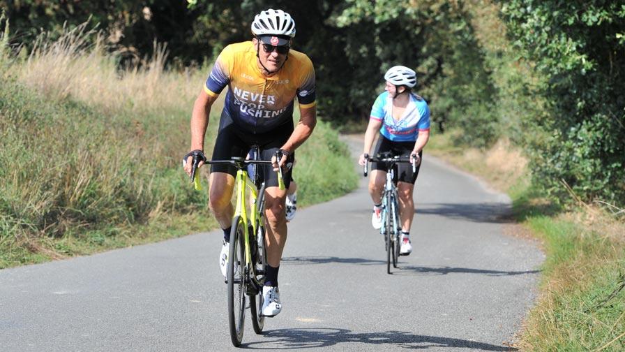 two cyclists riding hard out of the saddle