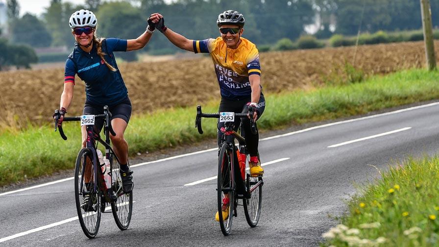 two cyclists riding side by side and holding hands