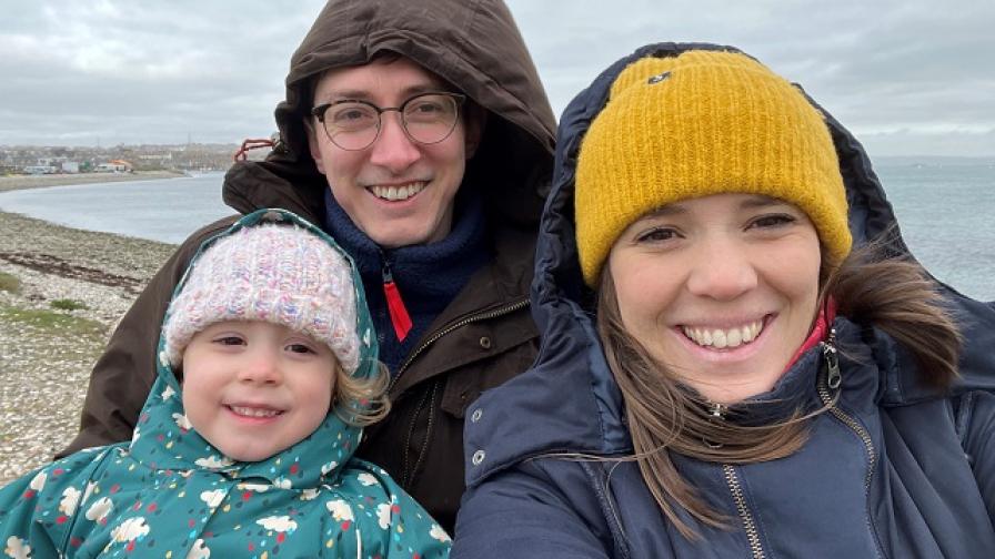 Eva and her parents with a stony beach in the background.