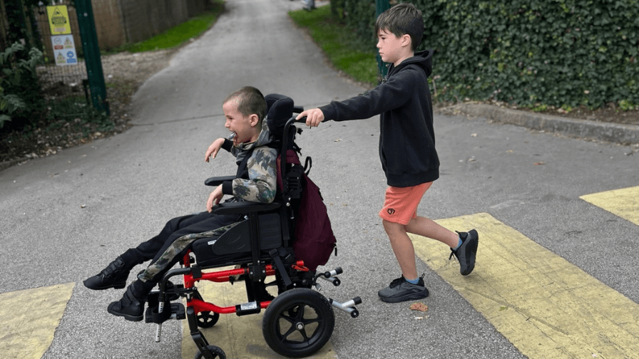 Mylo has been severely affected by CMV. Picture of his brother pushing him in his wheelchair.
