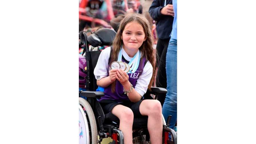 Image of Poppy in her chair with Frame Running medals