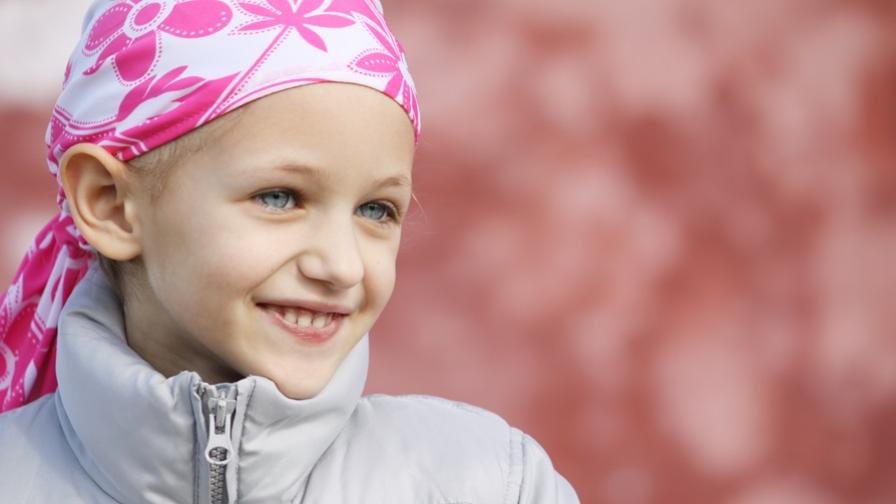 Young girl, who has lost her hair due to cancer treatment, wearing a pink head scarf.