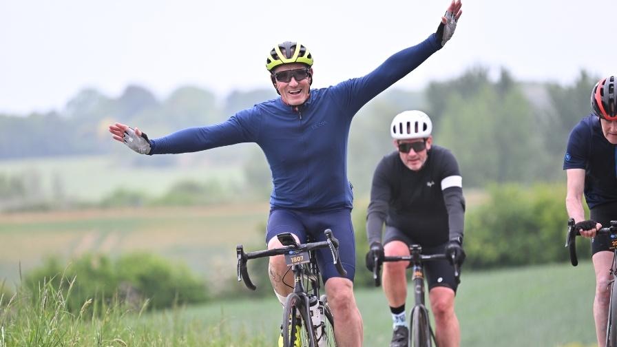 Cyclist celebrating with arms in the air as they cycle