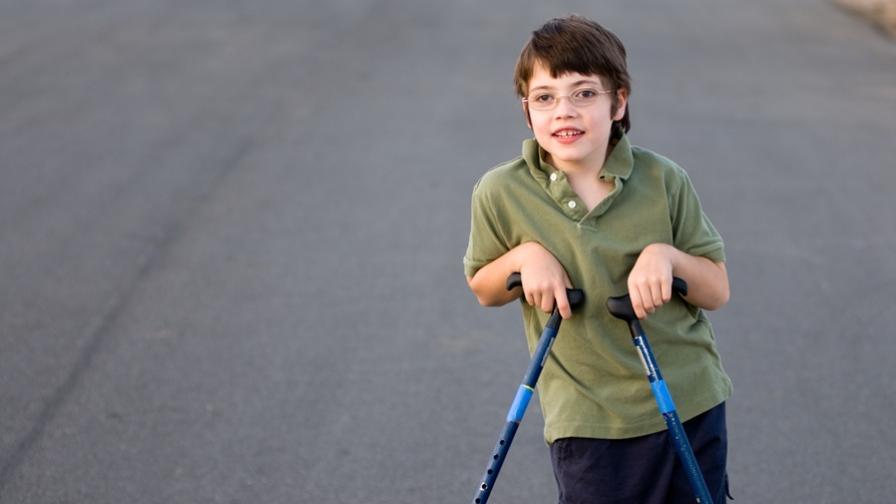 Boy, aged around nine or ten years old, using two walking sticks.