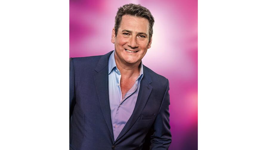 Profile picture of Tony Hadley ina blue suit on a pink background