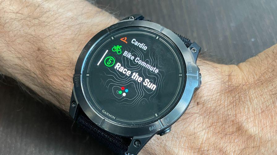 Close-up of a Garmin smartwatch on a person’s wrist displaying workout options including cardio, bike commute, and “Race the Sun.”