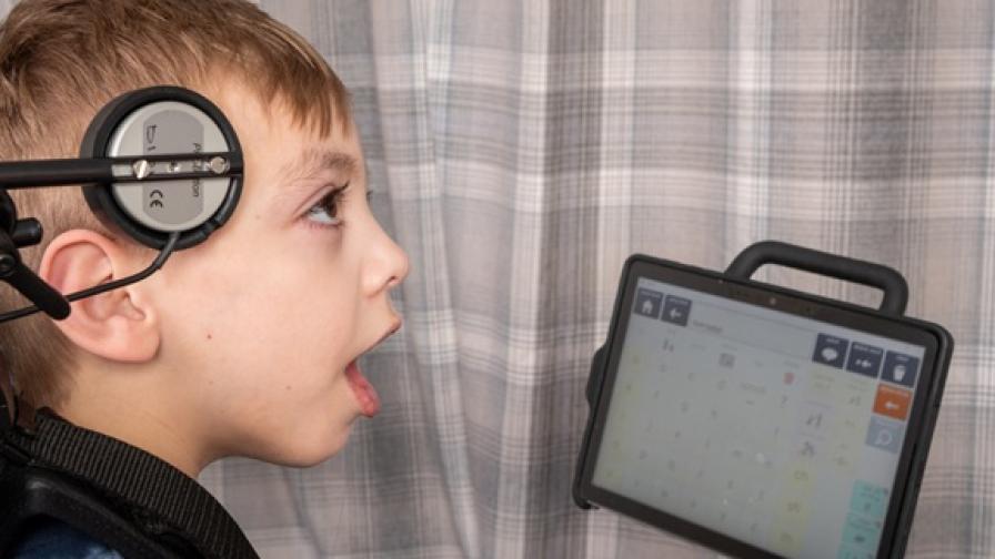 A young boy, aged around 10, who has cerebral palsy and is using an eye-gaze device to communicate.