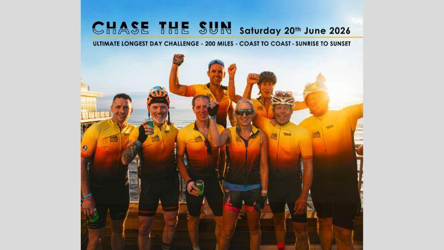 group of cyclists at a beachfront location punching the air in celebration for completing chase the sun with sun flare in the corner