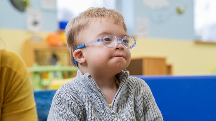 Very young boy with Down syndrome wearing glasses.