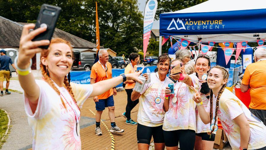 Teammates celebrate their achievement with a group selfie and drinks at the Race the Sun event village