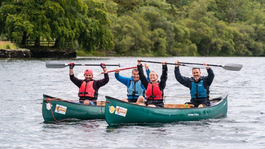 Teammates celebrating together in canoes during the water leg of the Race the Sun triple challenge