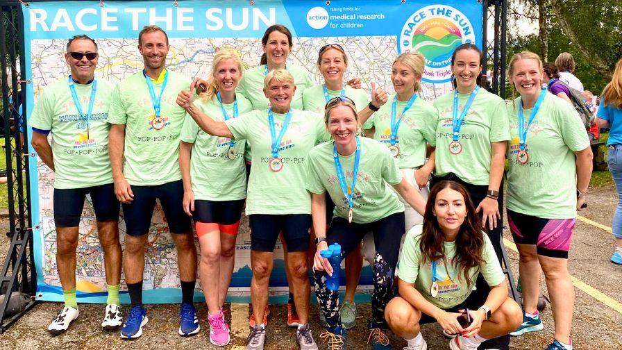 A group of ten colleagues smiling and wearing finishers