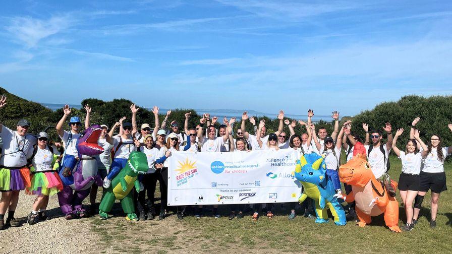 Corporate team and sponsors celebrate together with a banner and fun costumes during the Race the Sun challenge