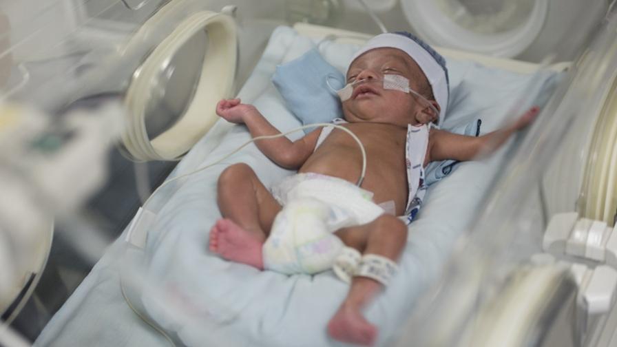 Image shows a premature baby boy in a hospital incubator, with several tubes attached.