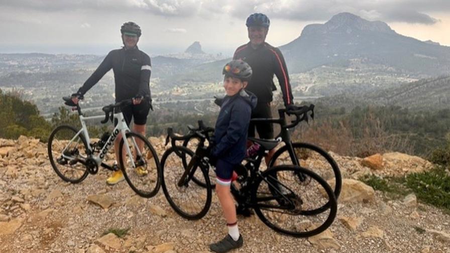 Image shows Sarah, Mike and Johnny Thomson with their bikes. There are mountains in the background.