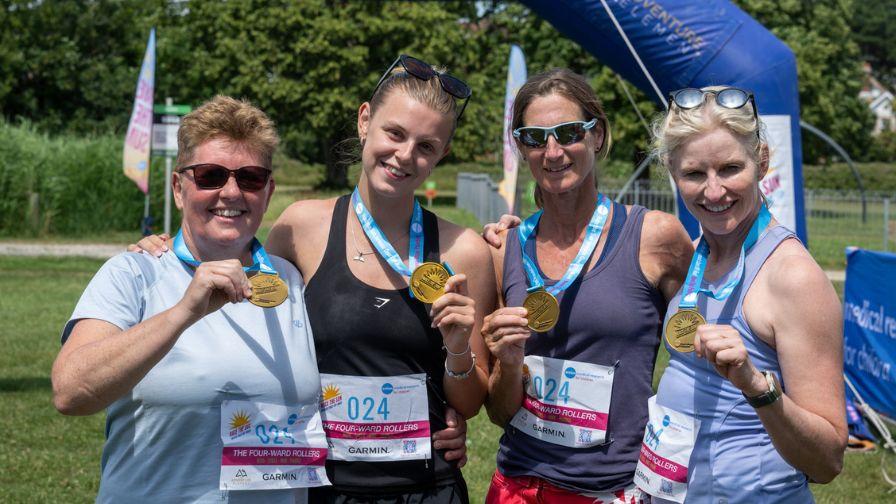 Four female athletes proudly showing off their race medals.