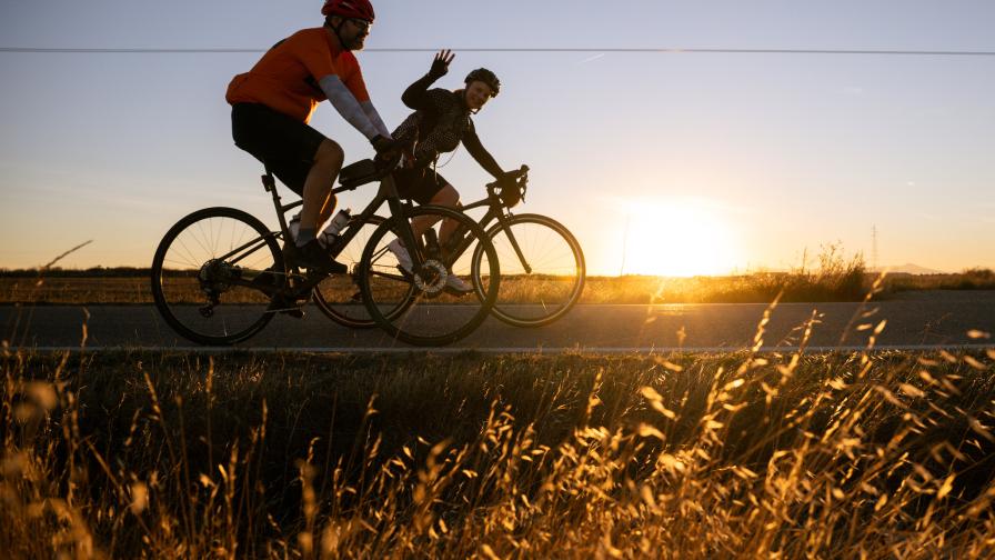 Two riders silhouetted against the setting sun with grass visible in the foreground