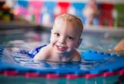 Aiden smiling at the camera while laying in a paddling pool