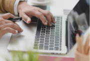 Hands typing on an open laptop