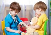 Two young children playing doctors with a teddy