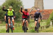 three cyclists waving to camera on ride suffolk