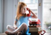 Young girl playing with a red telephone