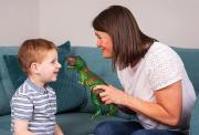 Evan and Mum sat on a sofa playing with a T-Rex toy