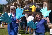 Two Action volunteers at an event waving with big blue Action foam hands
