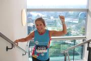 Lady climbing a stair case with large windows in the background showing the view from top of a skyscraper