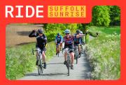 Group of cyclisted riding down a country lane with fields either side of the road