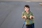 Boy, aged around nine or ten years old, using two sticks to walk.