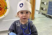 Young child wearing a toy nurse