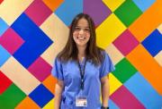 Image of Dr Eva standing in front of a colourful backdrop