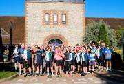 Image shows a large group of people in cycling clothes cheering as they get ready to embark on a charity bike ride.