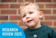 A young boy in a green sweater looks up against a brick wall. A blue corner graphic reads "RESEARCH REVIEW 2025".
