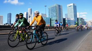 cyclists riding past canary wharf