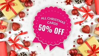 Wrapped christmas gift and selection of christmas decorations on a white background with small snowflakes. A badge reads "All Christmas Cards 50% off"